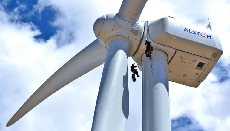 two people climb on wind turbine