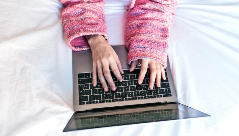 hands in knit sleeves type on laptop