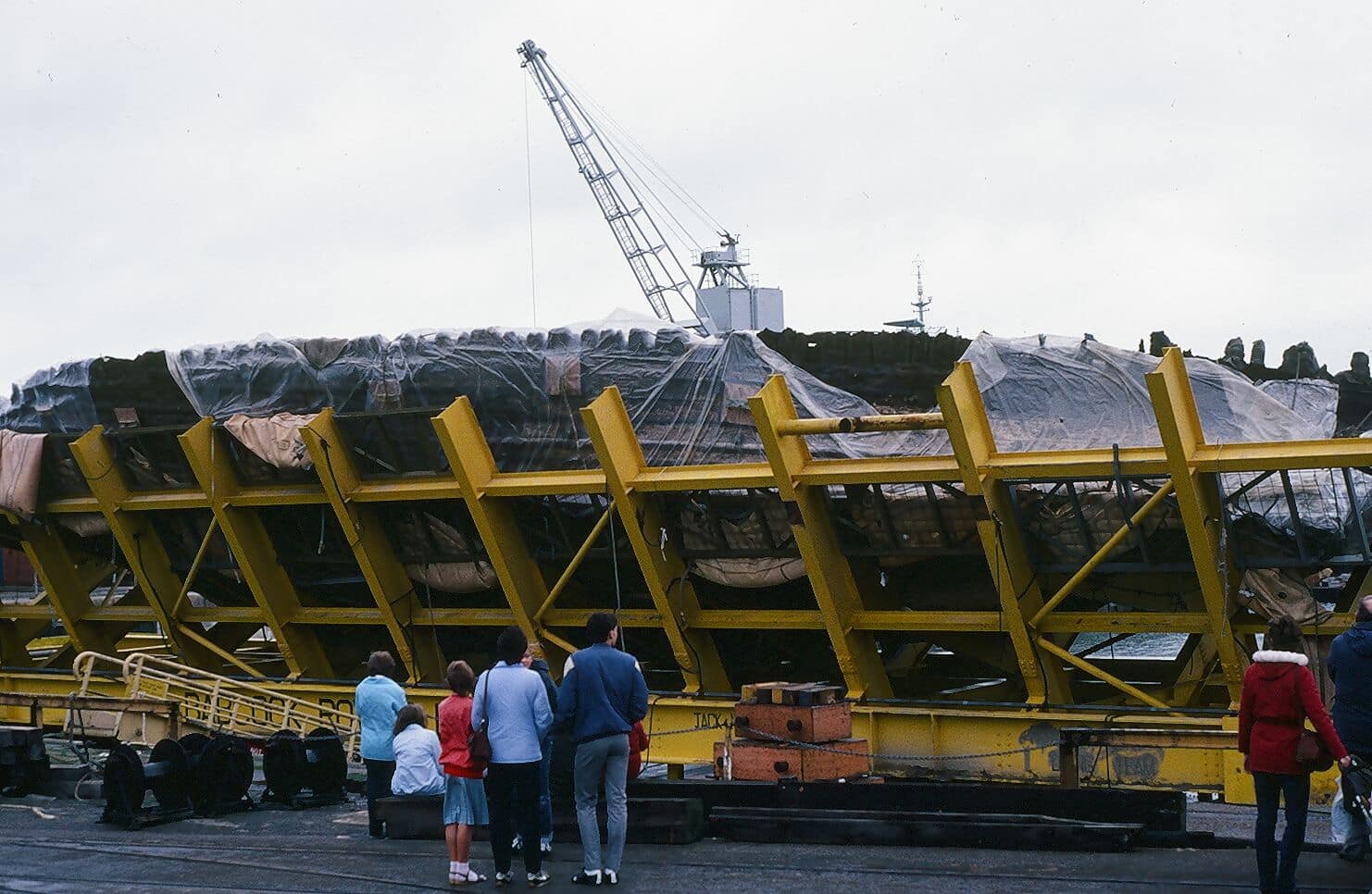 people stand in front of ship in metal frame