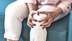 A woman clutches her knee in pain