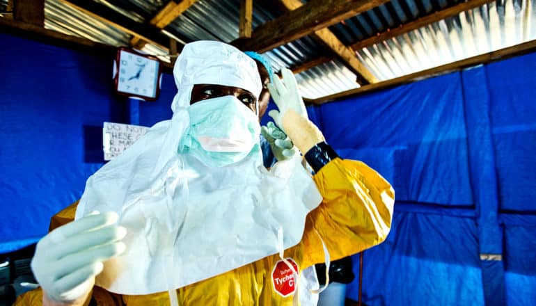 A health worker gets help in putting on protective gear