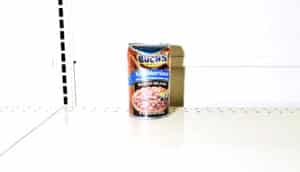 A single dented can of baked beans is the last on the grocery store shelf