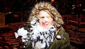 A woman outside gets hit in the face with a snowball