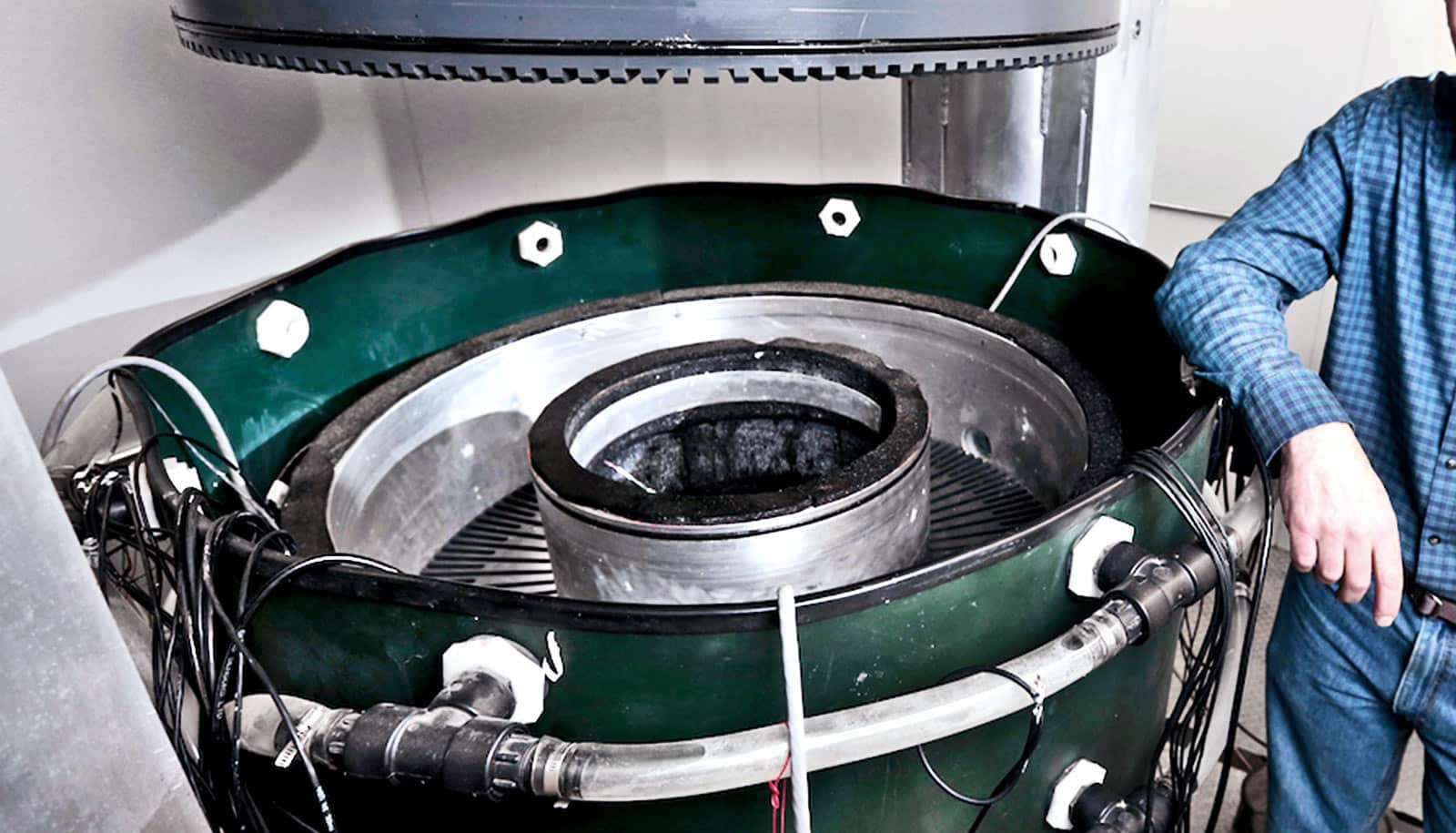 A researcher leans on the 9-foot tall machine, which is a circular drum that looks slightly like a turbine