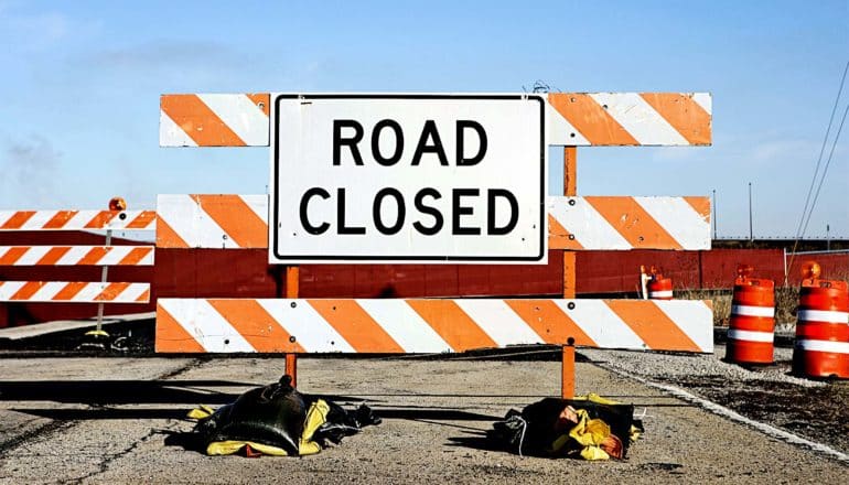 A road block with a sign that reads "Road Closed"