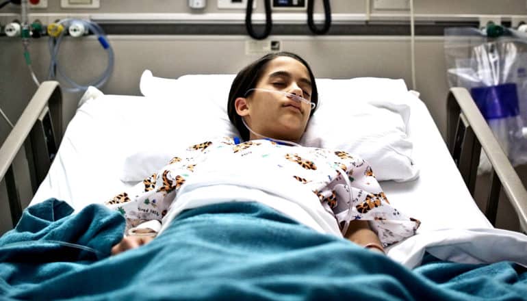 A child sleeps in a hospital with a breathing tube in their nose