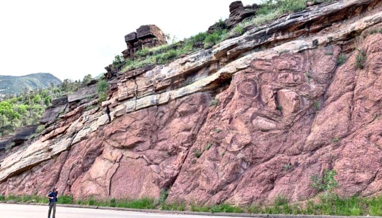 Macdonald looks tiny against the huge, red rock face