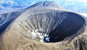 The volcano crater has white smoke coming from it
