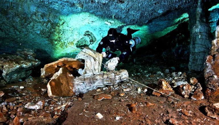 A diver in scuba gear writes notes while in the underwater mining cave