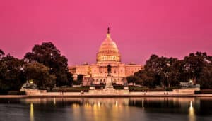 The US capitol building in Washington DC stands against a pink sky at sunset