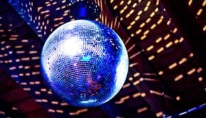 A disco ball hangs from a ceiling with light reflecting off it