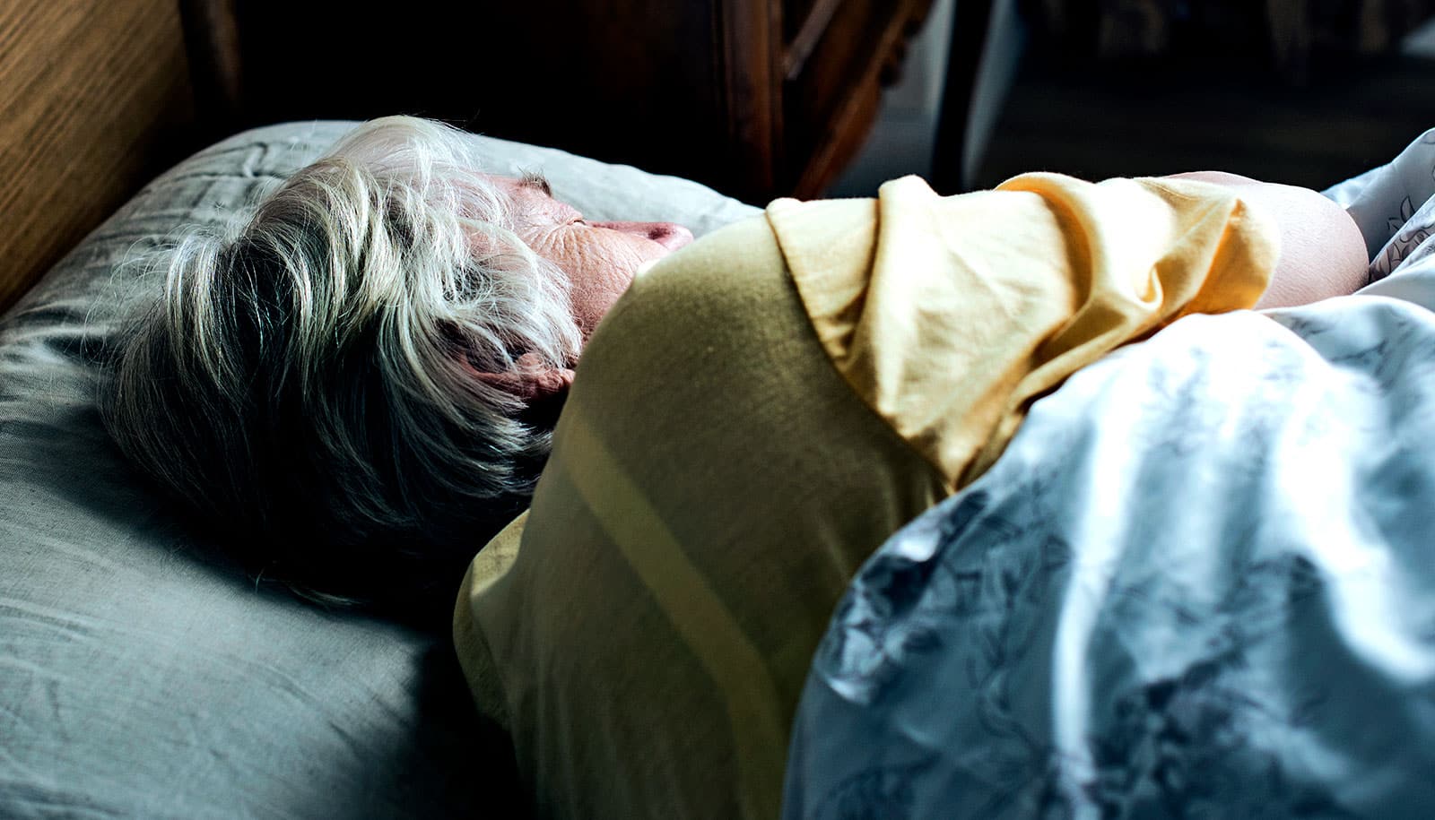 An elderly woman sleeps in bed