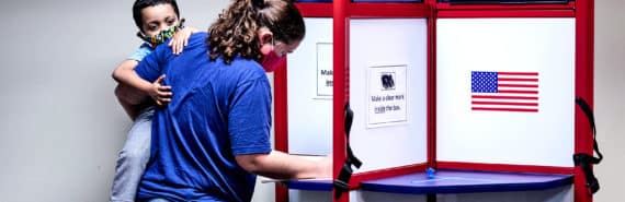 A voter holds her child while casting a ballot