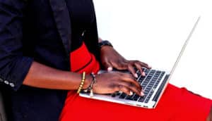 A woman types on a laptop sitting on her lap