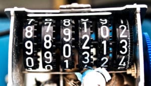 A broken date-making machine has several side-by-side black dials covered in numbers 0-9