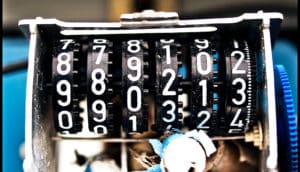 A broken date-making machine has several side-by-side black dials covered in numbers 0-9