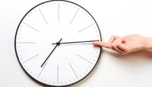 A person stops the hand of a clock with her finger