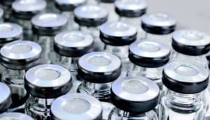 Glass vials with metallic lids sit in rows