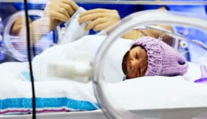 A baby in a bassinet in the NICU