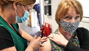 A health care worker gives a woman the COVID-19 vaccine