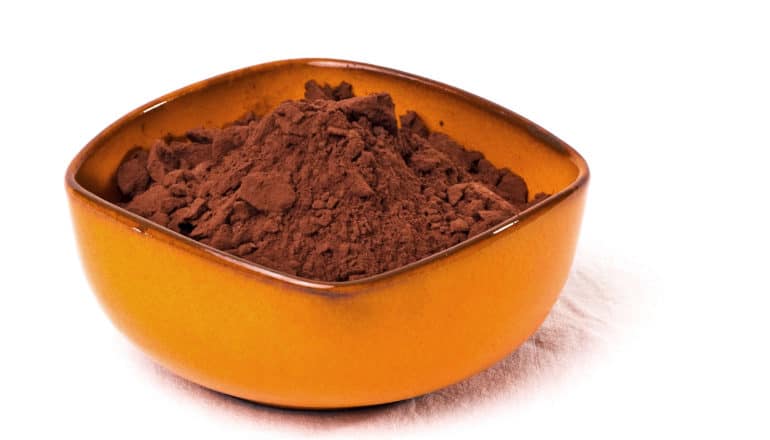 An orange bowl filled with brown cocoa powder