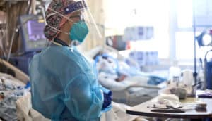 A health worker looks over several covid-19 patients in hospital beds