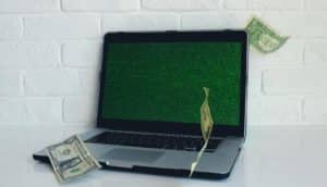 dollar bills fall around laptop
