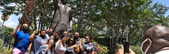 A group poses for a picture in front of a statue of Al Edwards