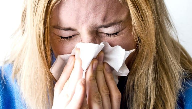 A woman sneezes into a tissue