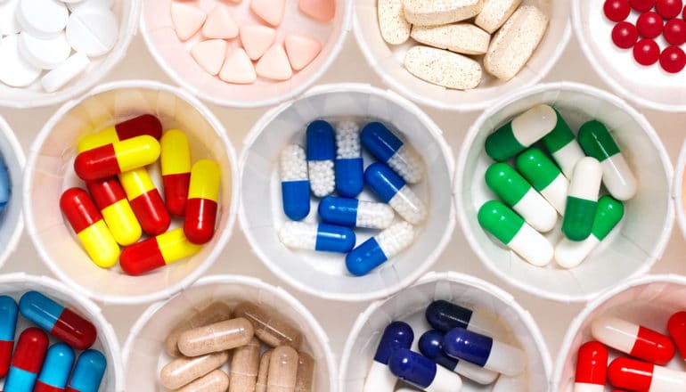 Many colorful pills sit in several paper cups