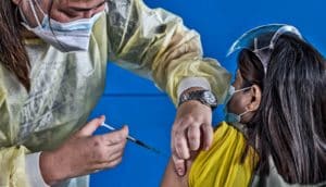 A health worker gives the COVID-19 vaccine to a woman sitting down