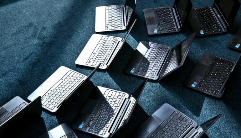 Many laptop computers spread out on a blue carpet