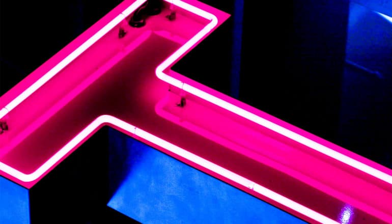 The letter T in pink neon light