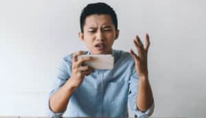 person holding phone looks frustrated