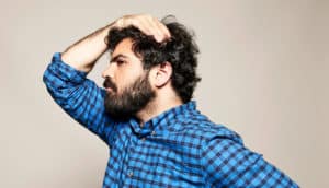 person looks thoughtful with hand on head