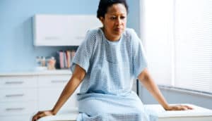 A woman sits in a doctor's office in a gown