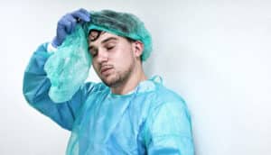 sweaty, tired person removes PPE