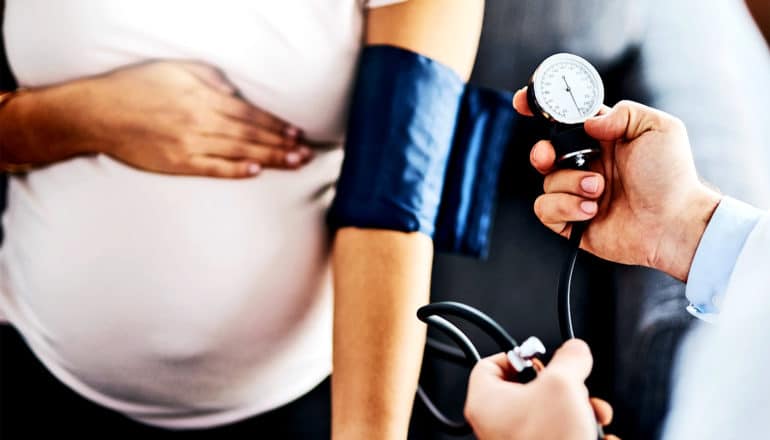 A pregnant woman gets her blood pressure checked by a doctor