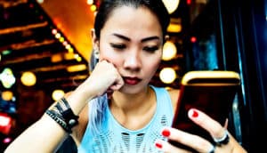 A woman rests her head on her fist as she reads her phone