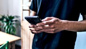 A man holds his phone as he stands in an apartment