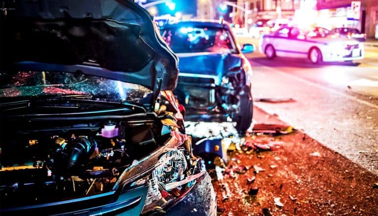 Two cars involved in a crash are pulled to the side of a city street while police arrive