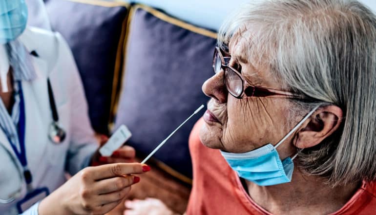 A nursing home resident gets ready for a nasal swab COVID-19 test