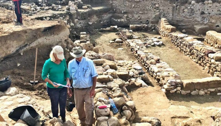 Researchers stand at the excavation site at Tall el-Hammam, which has low stone walls in a sunken pit