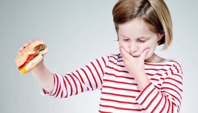 child holds hamburger away, looks disgusted
