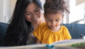 A woman reads a book with her young daughter
