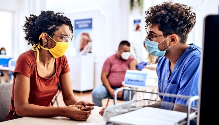 Een vrouw spreekt met een gezondheidswerker in een vaccinkliniek