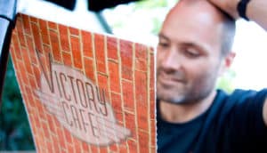 A man looking at a restaurant menu puts his hand on his head