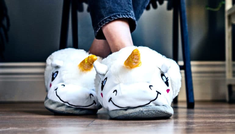 A woman wears white unicorn slippers under her desk