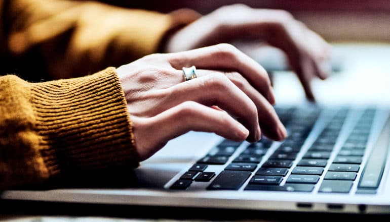 Een blanke vrouw typt op een laptop