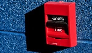 A red fire alarm box on a blue wall